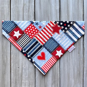 May include: A red, white, and blue patchwork bandana with stars and stripes. The bandana is made of cotton fabric and has a frayed edge. The bandana is a great way to show your patriotic pride.