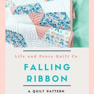 Puede incluir: Un patrón de colcha llamado "Falling Ribbon" de Elena Watson. La colcha está hecha con una variedad de telas florales y arcoíris en tonos de rosa, azul y blanco. La colcha está doblada y expuesta sobre un fondo rosa claro con lunares blancos.