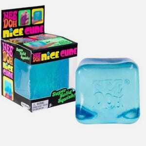 Könnte beinhalten: Ein blaues Nee Doh Nice Cube Spielzeug und seine Verpackung. Der Würfel ist ein durchscheinendes Blau mit dem geprägten Nee Doh-Logo auf der Oberfläche. Die Verpackung ist schwarz mit farbenfrohen Grafiken und den Worten "Nee Doh Nice Cube" und "Super Solid Squish!"