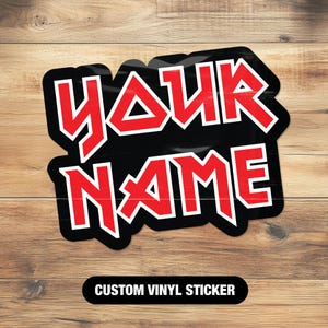 Pode incluir: Adesivo de vinil preto e vermelho com o texto "YOUR NAME" em uma fonte em negrito de inspiração metálica. Adesivo de vinil personalizado.