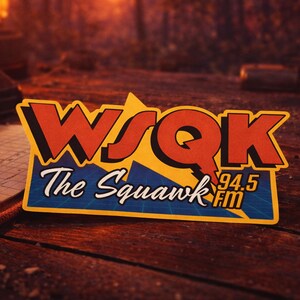 May include: A rectangular sticker featuring the text "WSQK The Squawk 94.5 FM". The sticker has a yellow and blue background with red and white lettering. The sticker is on a wooden surface.