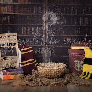 May include: A Harry Potter themed newborn photography backdrop with a brown wooden bookshelf, a newspaper with the headline "Boy Who Lived", a brown and gold striped scarf, a wicker basket, a stack of books, and a yellow and black striped scarf.