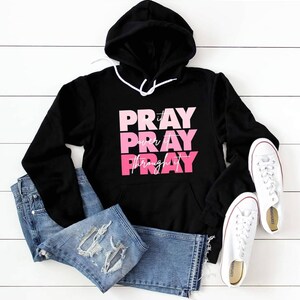 May include: Black hooded sweatshirt with a pink and white graphic that says "Pray it over it Pray through it".