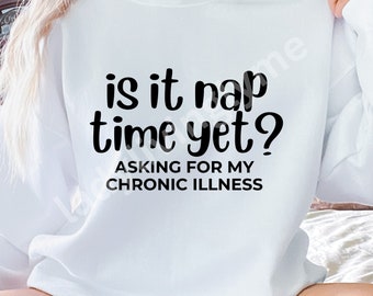 May include: White sweatshirt with black text that reads "is it nap time yet? asking for my chronic illness"