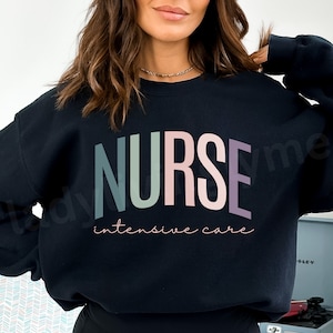 May include: A black sweatshirt with the word "NURSE" in large, colorful letters across the front. Below the word "NURSE" is the text "intensive care" in a cursive font. The sweatshirt is a crew neck style.