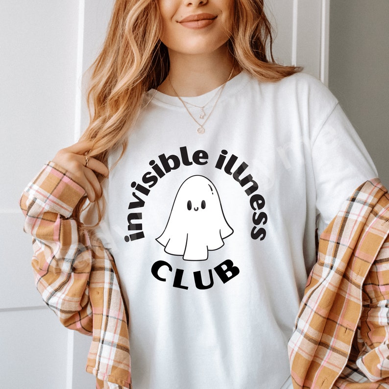 May include: White t-shirt with a black graphic of a ghost with the text "invisible illness club" around it.