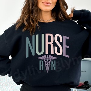 May include: Black sweatshirt with the word "NURSE" in rainbow colours and a medical caduceus symbol.