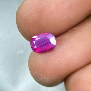 Può includere: Una gemma ovale di colore rosa vibrante con un motivo striato.