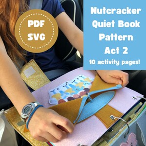 May include: A child's hands are shown holding open a felt quiet book with a blue and yellow zipper. The book has a pink background and features a felt illustration of a group of people. The book is titled "Nutcracker Quiet Book Pattern Act 2" and says "10 activity pages!" in the top right corner.