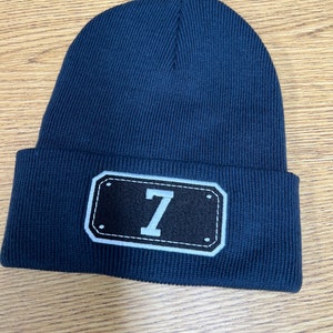 May include: A navy blue knit beanie with a black and white patch that says "7" on it.