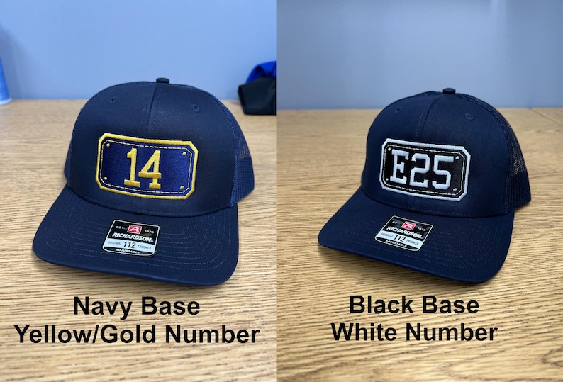 May include: Two adjustable trucker hats with mesh backs. The left hat is navy blue with a rectangular patch featuring the yellow number 14. The right hat is black with a rectangular patch featuring the white text E25. Both have Richardson labels.
