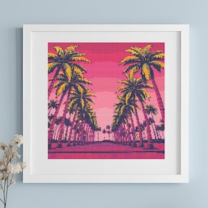 May include: A framed art print featuring a pixelated illustration of a palm tree-lined street under a pink and yellow sunset. The artwork is in a white frame, displayed on a white surface against a light blue wall. Decorative vases and flowers are in the foreground.