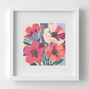 May include: A framed floral cross-stitch artwork. The artwork features a colorful arrangement of flowers in shades of pink, orange, and cream, with green stems and leaves. The artwork is set against a light yellow and blue background.