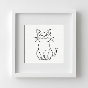 Può includere: Un punto croce incorniciato di un gatto. Il gatto è raffigurato con filo nero su sfondo bianco, con un design semplice, simile a un cartone animato. La cornice è bianca e quadrata e l'immagine è centrata.