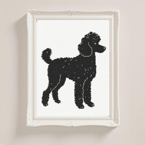 May include: A framed cross-stitch artwork showing a black poodle silhouette on a white background. The poodle is in profile, with a curly coat and a fluffy tail. The white frame has decorative detailing.