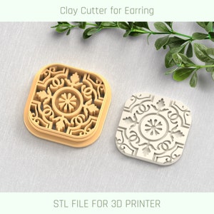 Op de afbeelding: Een 3D-geprinte kleiafsteker voor oorbellen, met een vierkant ontwerp en een gedetailleerd bloemenpatroon. De afsteker wordt getoond in zowel zijn natuurlijke bruine kleur als een witte versie. STL-BESTAND VOOR 3D-PRINTER.