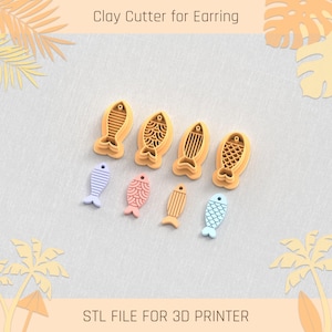 May include: A set of six 3D printed fish-shaped clay cutters for earrings. The cutters are in various designs, including striped, scaly, and patterned. The cutters are arranged in a row on a light gray surface. The text "STL FILE FOR 3D PRINTER" is printed below the cutters.
