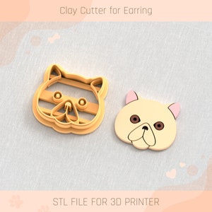 May include: Two 3D printed clay cutters for earrings, one with a striped cat face and the other with a white cat face. The text "STL FILE FOR 3D PRINTER" is at the bottom of the image.