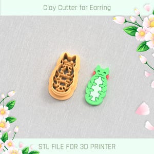 May include: Two 3D printed clay cutters shaped like cats. The cutter on the left is brown and the cutter on the right is green.