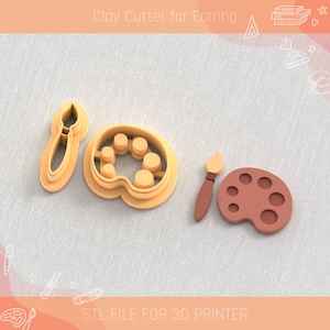 Puede incluir: Tres cortadores de arcilla impresos en 3D para pendientes, con forma de pincel, paleta de pintura y paleta de pintura con pincel. Los cortadores son de color naranja y marrón.