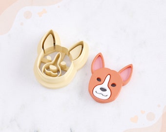 May include: A 3D printed dog head clay cutter for earrings. The cutter is beige and the printed dog head is orange. The text "STL FILE FOR 3D PRINTER" is at the bottom of the image.