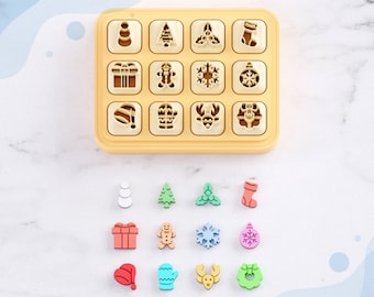 May include: A set of 16 Christmas-themed clay cutters for earrings. The cutters are arranged in a grid on a yellow plastic base. The cutters are in the shape of a snowman, Christmas tree, holly, stocking, gift box, gingerbread man, snowflake, ornament, Santa hat, mitten, reindeer, and wreath. The cutters are made for use with polymer clay.
