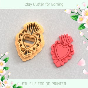 May include: A clay cutter for earrings in the shape of a heart with a flame design. The cutter is light orange, next to a red heart-shaped earring. The text "Clay Cutter for Earring" and "STL FILE FOR 3D PRINTER" are visible.
