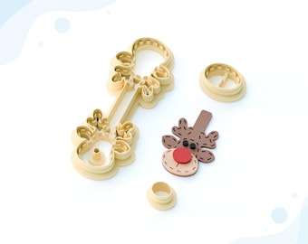 May include: A 3D printed clay cutter for earrings in the shape of a reindeer head. The cutter is made of beige plastic and has a red nose and black eyes. The cutter is designed to be used with polymer clay to create earrings.