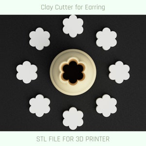 May include: A 3D printed clay cutter for earrings, shaped like a flower. The cutter is beige and has a five-petal flower design. There are eight cutters in total, arranged in a circle around the cutter in the center.