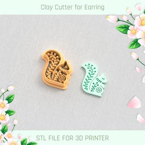 May include: Two clay cutters for earrings, one orange and one mint green, shaped like squirrels with floral designs. The orange cutter is a mold, while the green one is a finished product. Text at the top reads "Clay Cutter for Earring" and at the bottom "STL FILE FOR 3D PRINTER".
