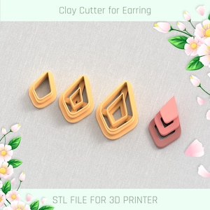 May include: A set of three clay cutters for earrings, featuring a diamond shape with different sizes. The cutters are made of a light orange plastic and are arranged on a light grey textured surface. The text "STL FILE FOR 3D PRINTER" is printed below the cutters.