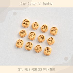 Può includere: Una collezione di taglierini in argilla arancione chiaro per orecchini, ognuno con un diverso simbolo zodiacale. Il testo "Clay Cutter for Earring" e "STL FILE FOR 3D PRINTER" sono visibili. I taglierini sono disposti su una superficie grigio chiaro.