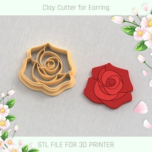 Puede incluir: Un cortador de arcilla en forma de rosa para pendientes, impreso en 3D. El cortador está hecho de plástico beige y se muestra junto a una rosa roja impresa en 3D.