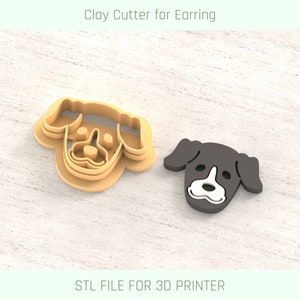 Op de afbeelding: Een 3D-geprinte koekjesuitsteker in de vorm van een hondenkop voor het maken van oorbellen van klei. De uitsteker is gemaakt van bruin plastic en wordt getoond naast een zwart-witte hondenkop-oorbel.