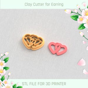 May include: Clay cutter for earrings in the shape of interlocking hearts. The cutter is light orange, and the cut-out heart is pink. The text "Clay Cutter for Earring" and "STL FILE FOR 3D PRINTER" are visible.