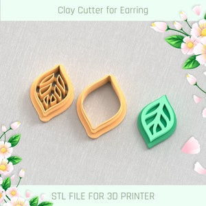 May include: Three clay cutters for earrings. Two are tan, leaf-shaped cutters, one with interior leaf vein details. The third is a green and light green leaf-shaped earring. Text at the top reads "Clay Cutter for Earring" and at the bottom "STL FILE FOR 3D PRINTER".