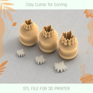 Può includere: Tre taglierini in argilla beige per orecchini, ciascuno con un design a forma di foglia d'acero sulla parte superiore e tre piccoli ritagli a forma di foglia. Il testo "Clay Cutter for Earring" e "STL FILE FOR 3D PRINTER" sono visibili.