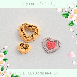 Op de afbeelding: Drie 3D-geprinte klei-uitstekers in de vorm van harten. De uitstekers zijn ontworpen voor het maken van oorbellen. De uitstekers zijn gemaakt van lichtbruin plastic. De tekst "Clay Cutter for Earring" en "STL FILE FOR 3D PRINTER" is zichtbaar in de afbeelding.