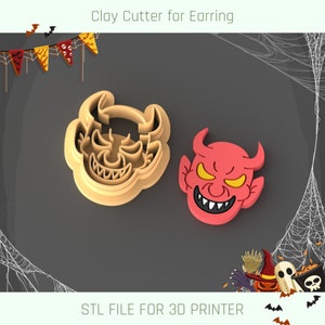 Puede incluir: Un cortador de arcilla beige con forma de cabeza de diablo, junto a una cabeza de diablo roja. El texto "Clay Cutter for Earring" y "STL FILE FOR 3D PRINTER" son visibles. Decoraciones de Halloween en el fondo.