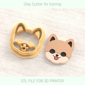 May include: A 3D printed clay cutter for earrings in the shape of a dog's head. The cutter is gold and the dog is brown with black eyes and a pink tongue. The text "STL FILE FOR 3D PRINTER" is below the image.