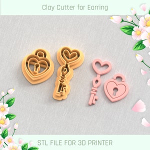Peut inclure: Un ensemble de trois emporte-pièces en plastique pour boucles d'oreilles, imprimés en 3D. Les emporte-pièces sont en forme de cadenas et de clé en forme de cœur. L'emporte-pièce du cadenas est rose et l'emporte-pièce de la clé est orange. Les emporte-pièces sont sur un fond de tissu gris clair. FICHIER STL POUR IMPRIMANTE 3D.