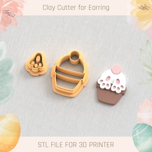 May include: Three 3D printed clay cutters for earrings, shaped like a cupcake, a bunny footprint, and a basket with a handle. The cutters are a light brown color and are designed for use with polymer clay.