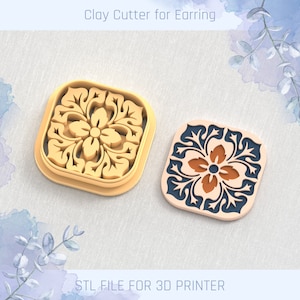 Puede incluir: Dos cortadores de arcilla impresos en 3D para pendientes, uno en dorado y otro en azul y naranja. Los cortadores tienen forma cuadrada con un diseño floral en el centro. El texto "STL FILE FOR 3D PRINTER" está en la parte inferior de la imagen.