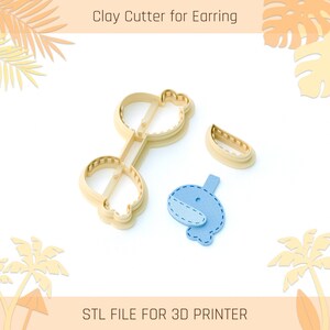 Może przedstawiać: Wycinak do gliny do kolczyków, z beżowym plastikowym wycinakiem w kształcie klucza i wieloryba. Obraz zawiera również niebiesko-biały kolczyk w kształcie wieloryba i wycinak w kształcie półksiężyca. Widoczny jest tekst "Clay Cutter for Earring" i "STL FILE FOR 3D PRINTER".