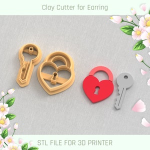 Puede incluir: Un archivo STL impreso en 3D para un juego de cortadores de arcilla con un candado en forma de corazón y una llave. El candado es rojo y la llave es gris. El cortador de arcilla está diseñado para hacer pendientes.