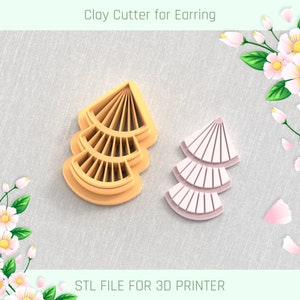 Puede incluir: Un cortador de arcilla en forma de abanico para pendientes y un pendiente rosa a juego. El cortador es de color naranja claro. El texto "Clay Cutter for Earring" y "STL FILE FOR 3D PRINTER" son visibles.