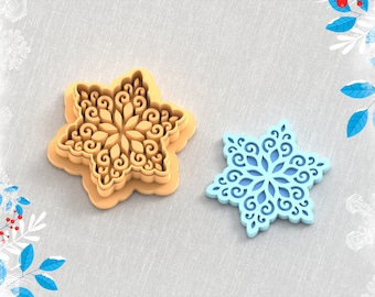 May include: A 3D printed clay cutter in the shape of a snowflake. The cutter is made of two pieces, one for the outer shape and one for the inner detail. The cutter is shown on a light gray fabric background. STL FILE FOR 3D PRINTER