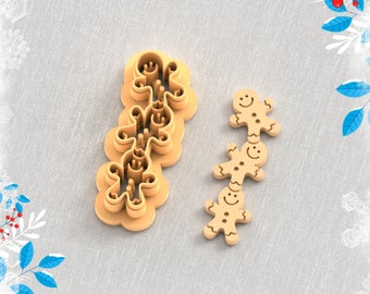 May include: A 3D printed gingerbread man clay cutter for earrings. The cutter is made of beige plastic and has a detailed gingerbread man design. The cutter is shown on a beige fabric background. STL FILE FOR 3D PRINTER.