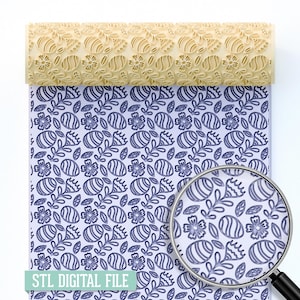 Può includere: Un mattarello beige con un motivo floreale è mostrato sopra un foglio con un motivo floreale blu abbinato. Le parole "STL DIGITAL FILE" sono stampate su un rettangolo verde chiaro in basso. Una lente d'ingrandimento è nell'angolo in basso a destra.