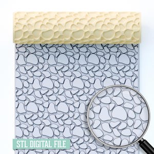 May include: A light yellow textured rolling pin with a pebble pattern sits above a sheet of paper with a matching pebble design. A magnifying glass shows a close-up of the pattern. The text "STL DIGITAL FILE" is at the bottom.